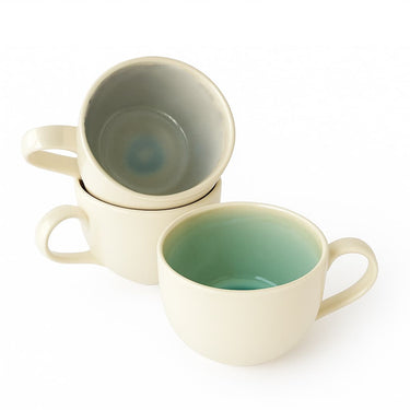 Two ceramic mugs, one beige and one green, on a white background