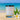 Candle with a label on a sandy beach with a tropical flower and ocean in the background