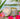 Candle with floral design and 'Kee Kast Candle & Bath Co' branding, surrounded by pink flowers.