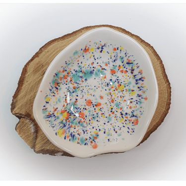 Ceramic dish with colorful speckles on a wooden base