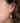 Close-up of a person wearing silver hoop earrings with intricate designs.