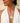 Silver heart-shaped pendant necklace worn by a person in a white top.
