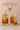 Three lit candles in glass bottles with floral designs on a pink background with 'TAURUS' text and zodiac sign.