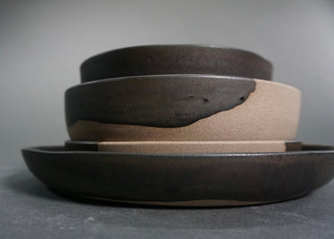 Stack of ceramic bowls with different shades of brown on a gray background
