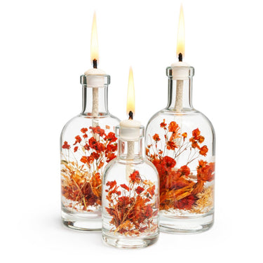 Three bottles with floral contents on a surface against a white background