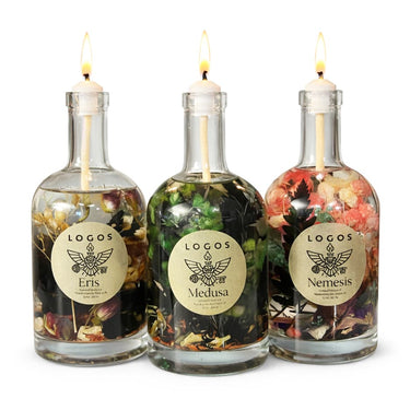 Three glass bottles with lit candles inside, featuring 'Logos' labels on a white background.
