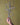Hand holding a metal decorative cross with heart shapes against a yellow background