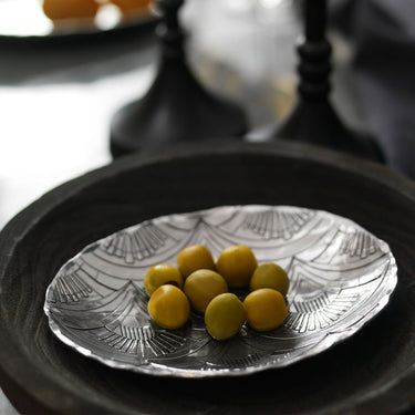 Decorative silver plate with yellow fruits on a dark surface