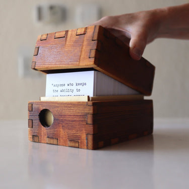 Wooden box with a card inside, held open by a hand on a neutral background