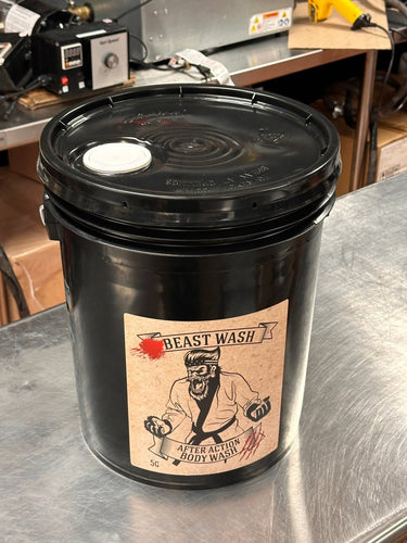 Black bucket labeled 'Beast Wash' on a metallic surface with workshop background