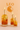 Three lit candles in glass bottles with herbs against a peach background with 'LEO' and lion symbol.