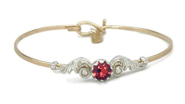 Gold and silver bracelet with a red gemstone on a white background