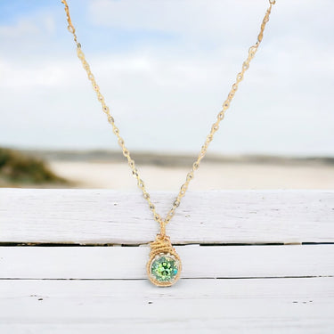 Gold necklace with a green gemstone pendant on a wooden surface