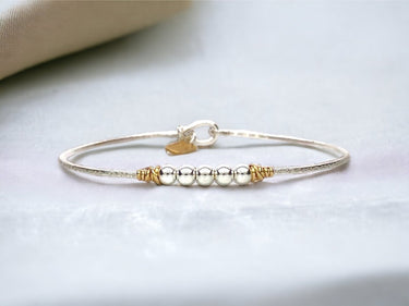 Gold bracelet with small beads on a light background