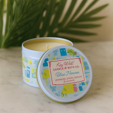 Key West Candle & Bath Co. candle with colorful label on a marble surface with green leaves in the background