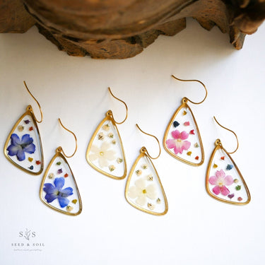 Teardrop-shaped earrings with floral designs on a white surface.