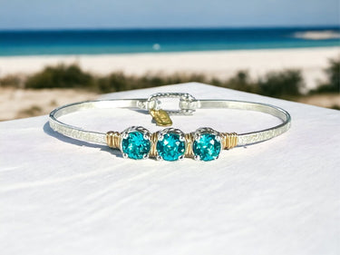 Bracelet with turquoise stones on a white shell with a beach background