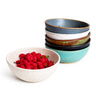 Set of ceramic bowls with a bowl of raspberries on a white background