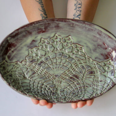 Person holding a ceramic plate with intricate lace-like design