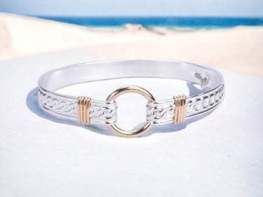 Silver bracelet with gold accents on a sandy beach