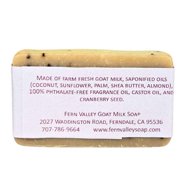 Bar of Cranberry Pomegranate Goat Milk Soap with a label detailing ingredients and contact information on a white background