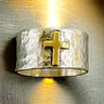 Silver ring with a gold cross on a textured surface