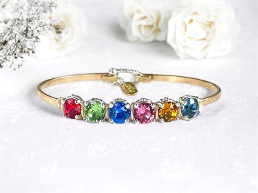 Gold bracelet with colorful gemstones on a white background