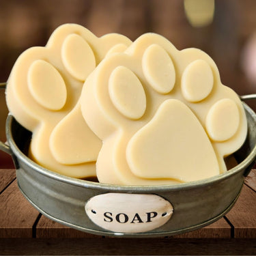 Paw-shaped soap bars in a metal container with a 'SOAP' label on a wooden surface.