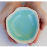 Hand holding a heart-shaped ceramic dish with a blue interior