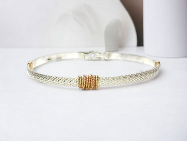 Silver bracelet with gold accents on a white background