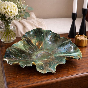 Emerald City Blossom Bowl on a wooden surface with flowers and candles in the background