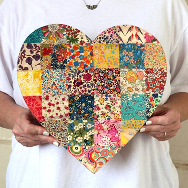 Heart-shaped patchwork wall hanging held by a person