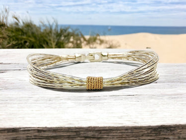 Gold bracelet on a wooden surface with a beach background
