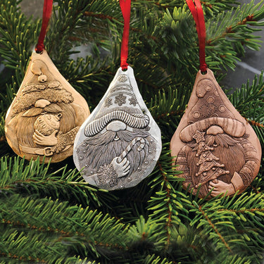 Three decorative gnome ornaments hanging on a Christmas tree.