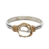 Silver ring with a gold rope design and pearl center on a white background