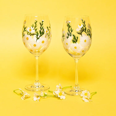 Two Hand-Painted Daisy Wine Glasses with floral designs on a yellow background