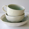 Stack of ceramic bowls on a white plate with a white background