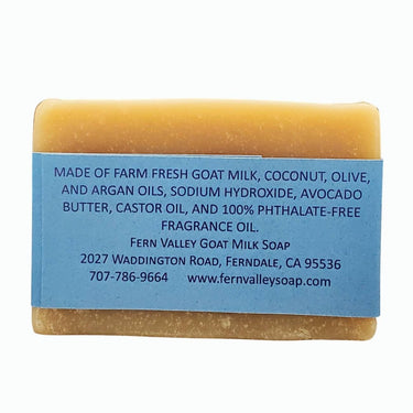 Bar of soap with a blue label detailing ingredients and contact information on a white background