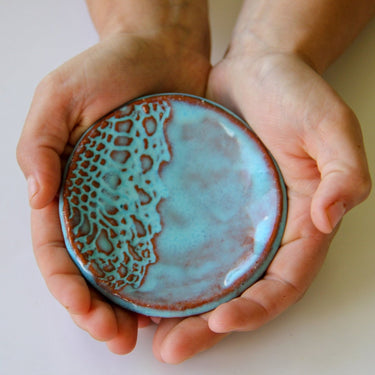 Hands holding a ceramic ring dish with textured surface