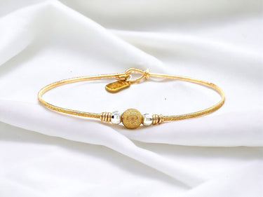 Gold bracelet with decorative beads on a white fabric background