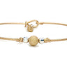 Gold bracelet with a spherical charm on a white background