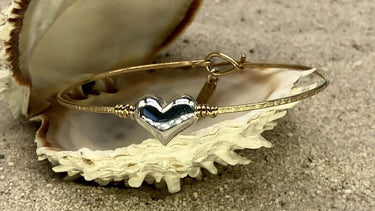Heart-shaped brooch inside an open shell on sand