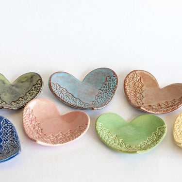 Set of ceramic heart-shaped dishes in various colors on a white background