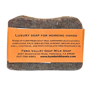Bar of Natural goat milk hand soap for mechanics and gardeners with an orange label on a white background