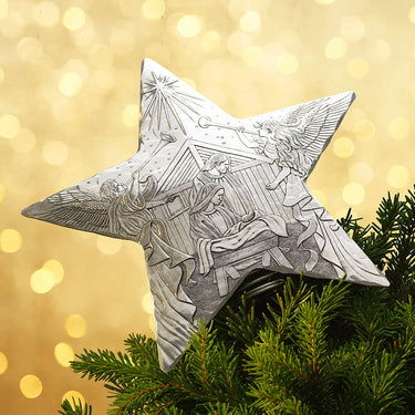 Decorative star ornament with religious design on a Christmas tree against a gold bokeh background