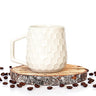 White textured mug on a wooden coaster with scattered coffee beans