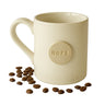 Beige mug with 'HOPE' button and scattered coffee beans on a white background