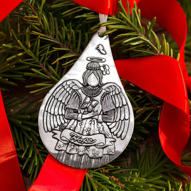Silver angel ornament on a red ribbon with greenery