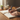 Person writing in a notebook with a steaming cup of coffee in the background