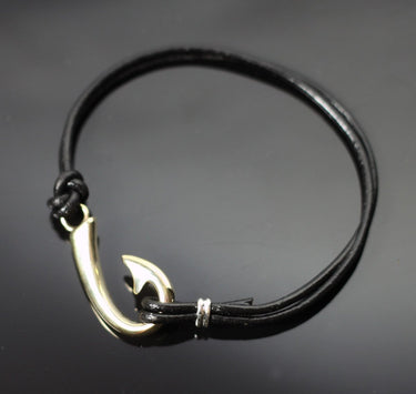 A black leather bracelet featuring a polished Bronze fishhook charm, displayed on a dark reflective surface.